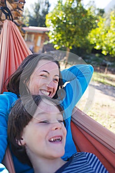 A boy with his mother are lying in a hammock in the courtyard of the house