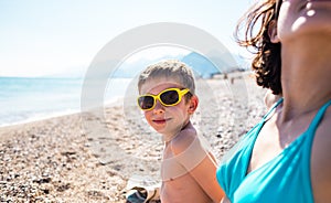 The boy with his mother sunbathe on the beach