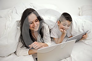 boy, And his mother is working on a laptop computer, The little boy put the tablet in his hand and turned to his busy