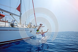 Boy with his sister jump of sailing yacht on summer cruise. Travel adventure, yachting with child