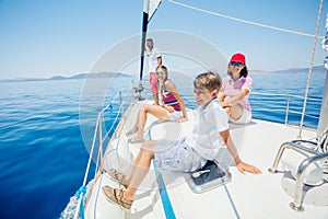 Boy with his sister and mother on board of sailing yacht on summer cruise.