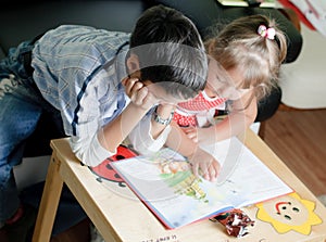 A boy and his sister are reading a book