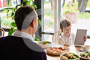 A boy with his tablet sitting at the dinner table