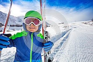 Close smiling portrait of a boy with ski on slope