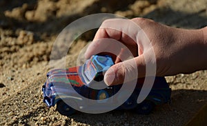 Boy hold in small hand old car model scuffed and differently colored in several layers of paint creates rainbow variations blue