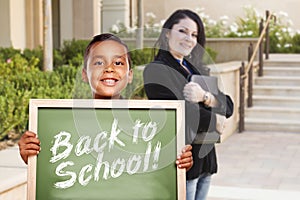 Boy Holding Back To School Chalk Board with Teacher Behind