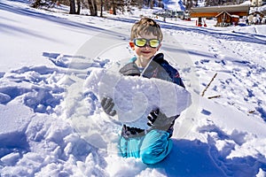 A boy holding a big piece of snow. Child playing with snow in frosty winter park