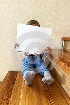 A boy is holding a clean white sheet of paper