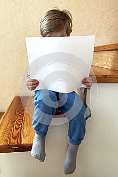 A boy is holding a clean white sheet of paper