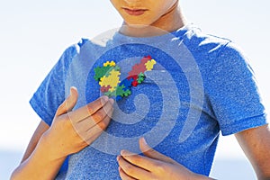Boy holding colorful puzzle autism awareness heart in his hands