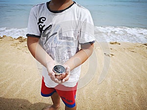 A boy holding a compass showing the direction point to north.