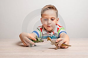 Boy holding dinosaur toys. Concept of developing attention in children through play