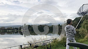 Boy holding fishing net. Beautiful fish pond near Badin, Banska Bystrica, Slovakia. Fishing place. Clouds over the lake.