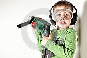 Boy holding green drilling machine on his shoulder