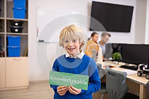 Boy holding green sign with word knowledgeable