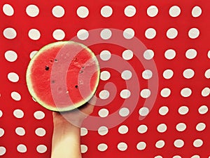 Boy holding half watermelon on red background