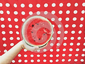 Boy holding half watermelon on red background