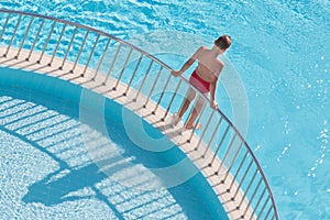 Boy holding the handrail and is going to dive