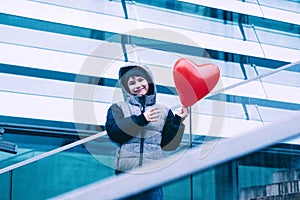 Boy holding heart shaped balloon in urban architecture