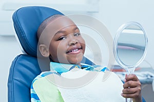 Boy holding at mirror in the dentists chair