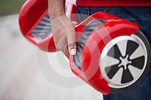 Boy holding modern red electric mini segway or hover board scooter