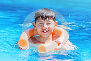 Boy holding on the pool noodle buoy for safety.