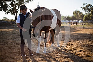 Boy holding the reins of a horse in the ranch photo