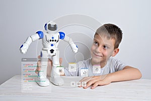 Boy is holding a robot in his hand with conceptual robot programming code