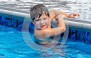 Boy holding safely to the edge of a pool