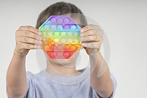 Boy holding sensory pop it fidget toy in his hands. Push pop-it fidgeting game helps relieve stress, anxiety