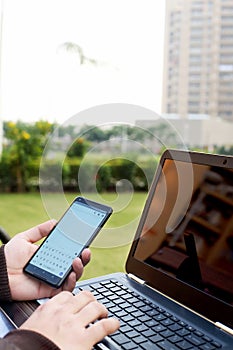 Boy is holding smartphone in hand with using laptop