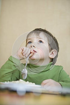 Boy Holding Spoon While Looking Up At Table