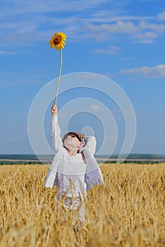 Boy holding a sunflower in the middle of a field