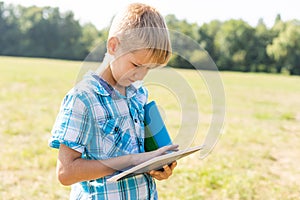 boy holding tablet PC on green grass lawn with copy space.