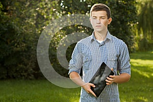 Boy holding tablet PC on green grass