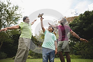 Boy holding toy airplane with father and son at park