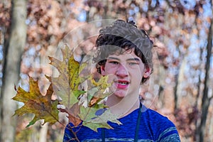 Boy Holding Up a Bunch of Oak Leaves in Forest