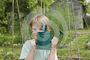 Boy Holding Watering Can In Garden