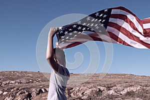 A boy holding waving US flag, beeng a patriot concept