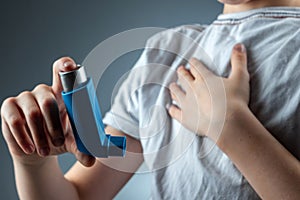 The boy holds an asthma inhaler in his hands to treat inflammatory diseases, shortness of breath. The concept of treatment for