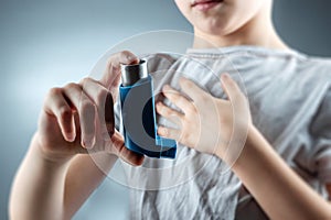 The boy holds an asthma inhaler in his hands to treat inflammatory diseases, shortness of breath. The concept of treatment for