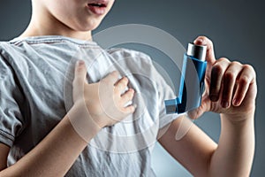 The boy holds an asthma inhaler in his hands to treat inflammatory diseases, shortness of breath. The concept of treatment for