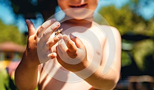 the boy holds a bee in his hand.
