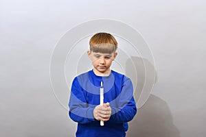 The boy holds a burning candle in front of him and looks at it. Easter service of idolatry