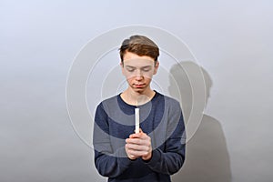 The boy holds a burning candle in front of him and looks at it. Easter service of idolatry