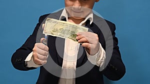 The boy holds a burning lighter in his hands and lights a hundred dollar bill. Dollars are on fire.