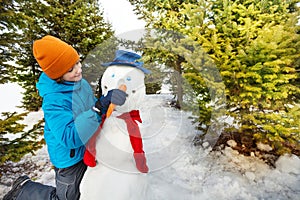 Boy holds carrot to put as nose of snowman