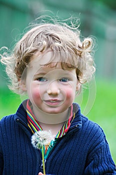 Boy holds a dandelion in hands