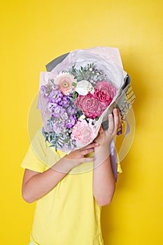 The boy holds a flower arrangement in a round box. A gift for Mom