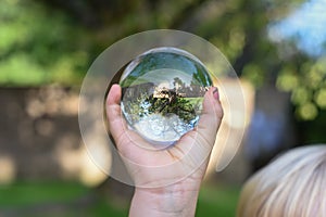 A boy holds a glass ball with reflection of a tree as an environmental conservation concept